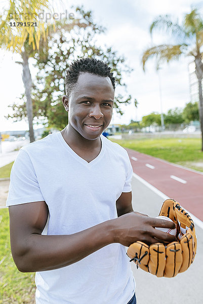Portrait des lächelnden jungen Mannes mit Ball und Baseballhandschuh