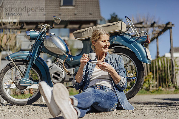 Lächelnde Frau bei einer Kaffeepause auf dem Oldtimer-Motorrad
