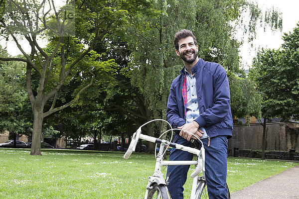 Lächelnder junger Mann mit Fahrrad im Park