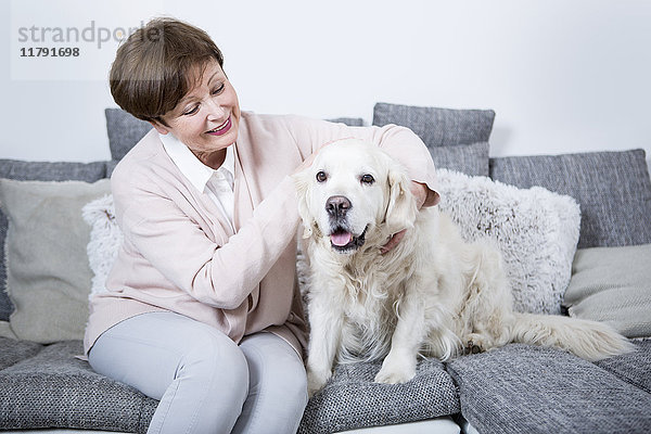 Seniorin auf der Couch sitzend mit ihrem Hund