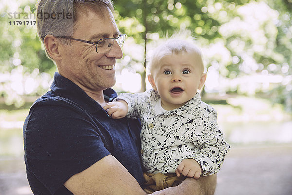 Lächelnder Vater hält verblüfftes Baby im Freien