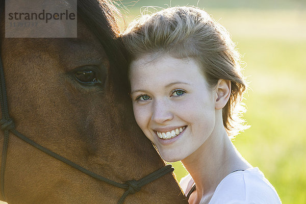 Porträt der glücklichen jungen Frau mit Pferd