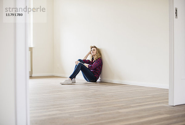 Junge Frau im neuen Zuhause auf dem Boden sitzend