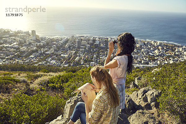 Südafrika  Kapstadt  Signal Hill  zwei junge Frauen mit Karte und Fernglas mit Blick auf die Stadt und das Meer