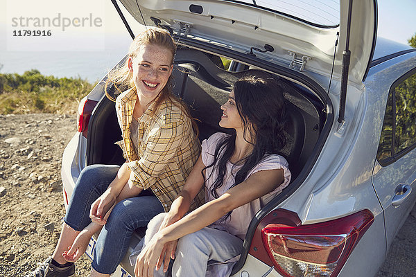 Südafrika  Kapstadt  Signal Hill  zwei junge Frauen sitzen im Kofferraum eines Autos