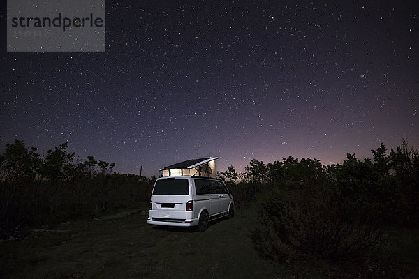 Wohnmobil mit Dachzelt in der Natur unter Sternenhimmel
