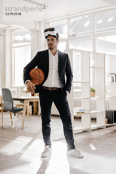 Geschäftsmann mit VR-Brille hält Basketball im Amt