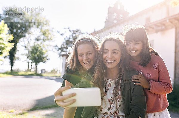 Drei glückliche Mädchen  die mit einem Selfie nach draußen gehen.