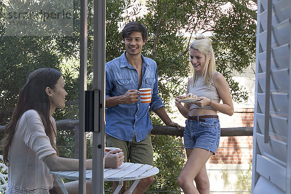 Lächelnde Freunde mit Kaffee auf der Veranda