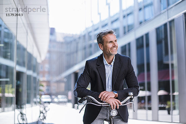 Lächelnder Geschäftsmann auf dem Fahrrad in der Stadt