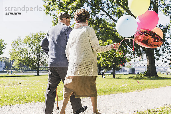 Rückansicht des Seniorenpaares mit Luftballons im Park