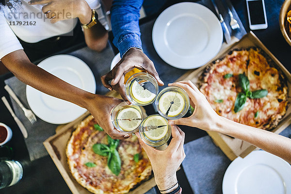 Gruppe von Freunden mit Pizza und klirrendem Wasser zu Hause