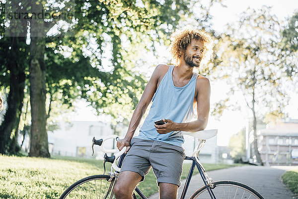 Mann mit Bart und lockigem Haar mit Fahrrad im Park