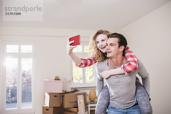 Glückliches junges Paar in neuem Zuhause mit einem Selfie