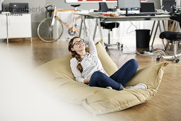 Junge Frau entspannt im Bohnensack im Büro