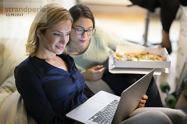 Zwei Geschäftsfrauen im Büro mit Pizza und Laptop