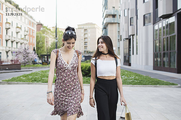 Zwei glückliche junge Frauen  die in der Stadt spazieren gehen.