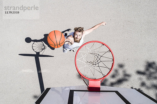Mann spielt Basketball auf dem Freigelände
