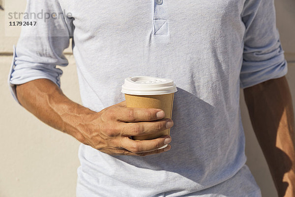 Junger Mann mit einer Tasse Kaffee zum Mitnehmen