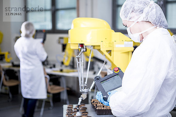 Frau in der Fabrik untersucht Roboter beim Umgang mit Cookies