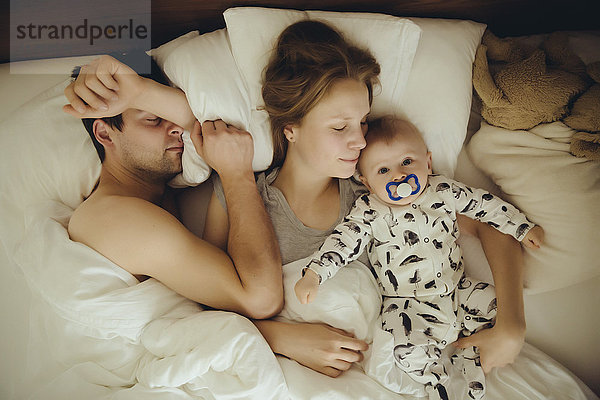 Mutter  Vater und Junge kuscheln im Bett