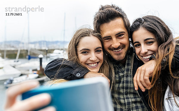 Drei Freunde  die einen Selfie am Yachthafen nehmen.
