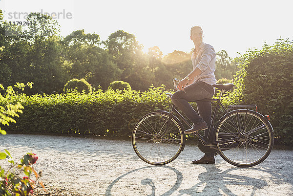 Mann mit Fahrrad im Park bei Sonnenaufgang