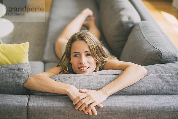 Porträt einer jungen Frau  die sich zu Hause auf der Couch entspannt.