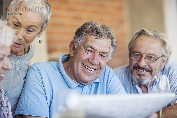 Porträt eines lächelnden älteren Mannes  der sich mit seinen Freunden amüsiert.