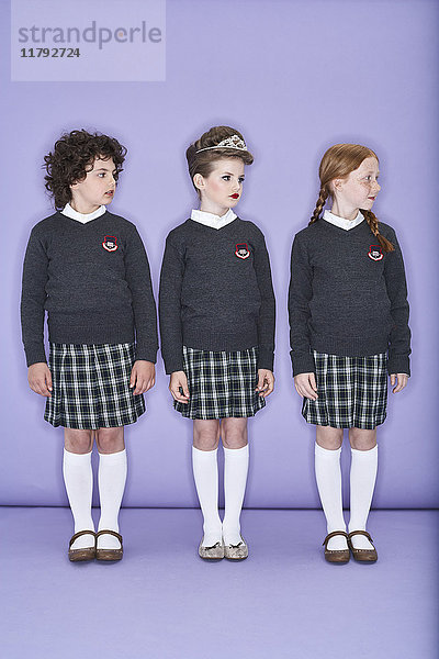 Drei Mädchen in Schuluniform stehen nebeneinander.