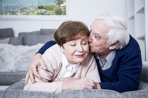Seniorenpaar auf der Couch liegend  umarmend und küssend