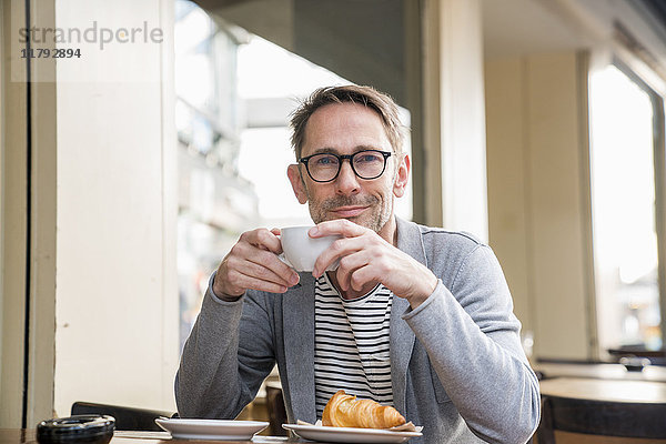 Porträt eines lächelnden  reifen Mannes beim Kaffeetrinken in einem Straßencafé