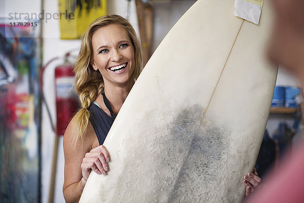 Surfboard Shaper Workshop  Mitarbeiterin lächelt mit Surfboard