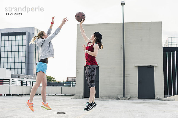 Zwei Frauen spielen Basketball auf Parkdeck in der Stadt