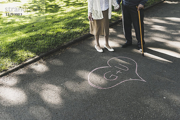 Senior Paar gezeichnet Liebe Herz mit Initialen auf Asphalt