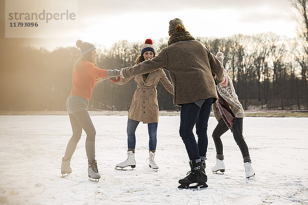 Freunde Eislaufen im Kreis auf dem zugefrorenen See