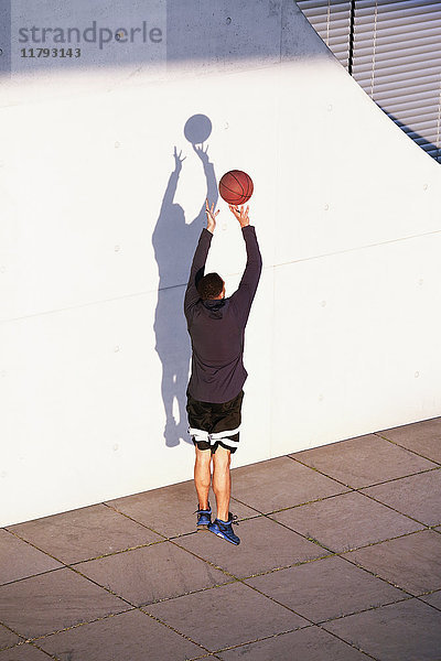 Junger Mann spielt Basketball in der Stadt