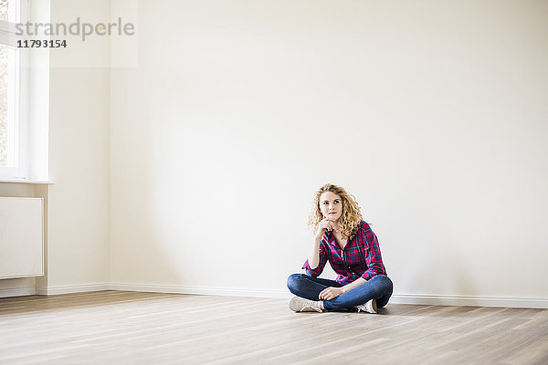 Junge Frau im neuen Zuhause auf dem Boden sitzend