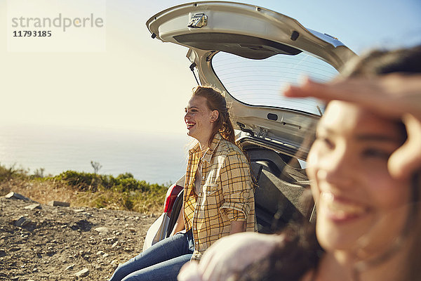 Südafrika  Kapstadt  Signal Hill  zwei glückliche junge Frauen an einem Auto an der Küste
