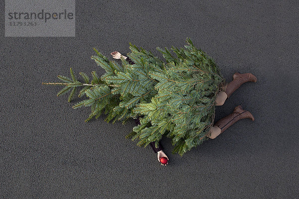 Frau liegt unter dem Weihnachtsbaum begraben
