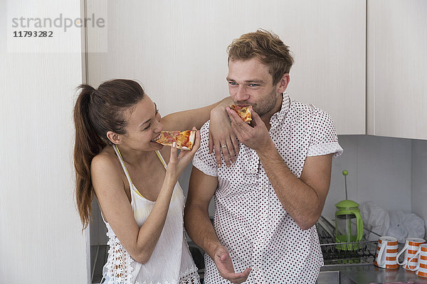 Glückliches junges Paar beim Pizzaessen in der Küche