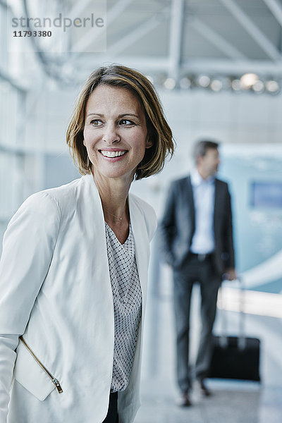 Lächelnde Geschäftsfrau am Flughafen mit Blick zur Seite