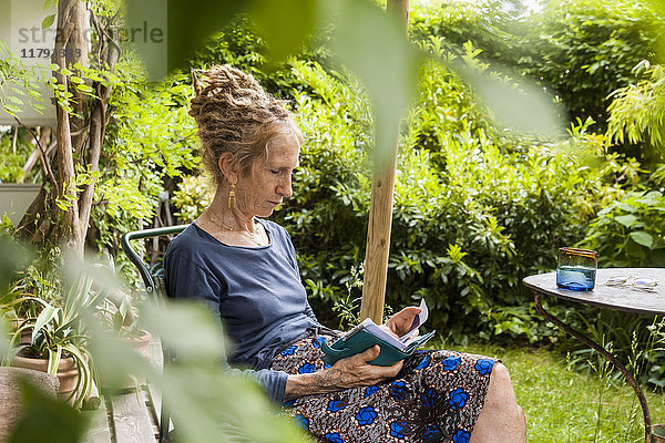 Seniorin mit Dreadlocks im Garten mit Blick auf den Terminplaner