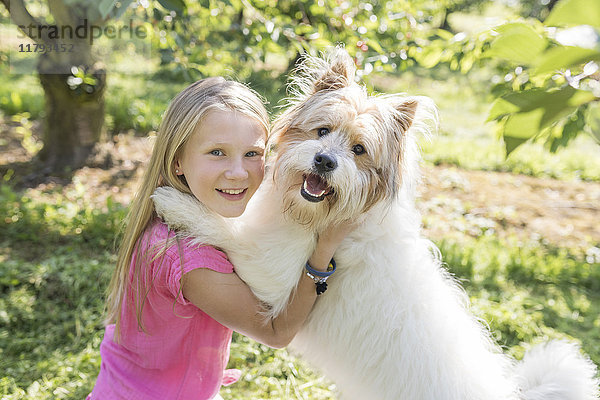 Mädchen spielt mit Hund auf der Wiese