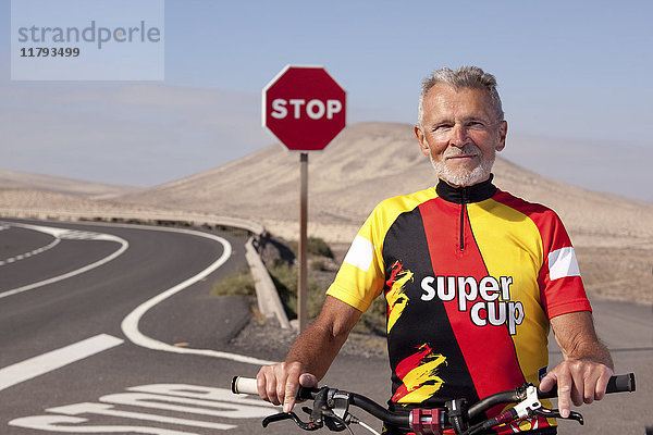 Spanien  Kanarische Inseln  Fuerteventura  Portrait eines selbstbewussten Senioren mit Mountainbike