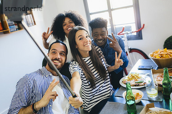 Gruppe von Freunden  die für einen Selfie am Esstisch zu Hause posieren.