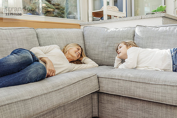 Reife Frau und Mädchen zu Hause auf der Couch liegend