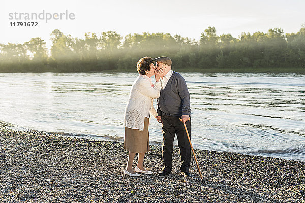 Glückliches Seniorenpaar beim Küssen am Strand
