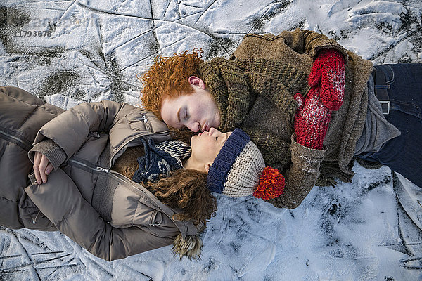 Paar auf gefrorener Seeoberfläche liegend küssend