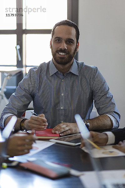 Porträt eines lächelnden Geschäftsmannes bei einer Besprechung im Büro